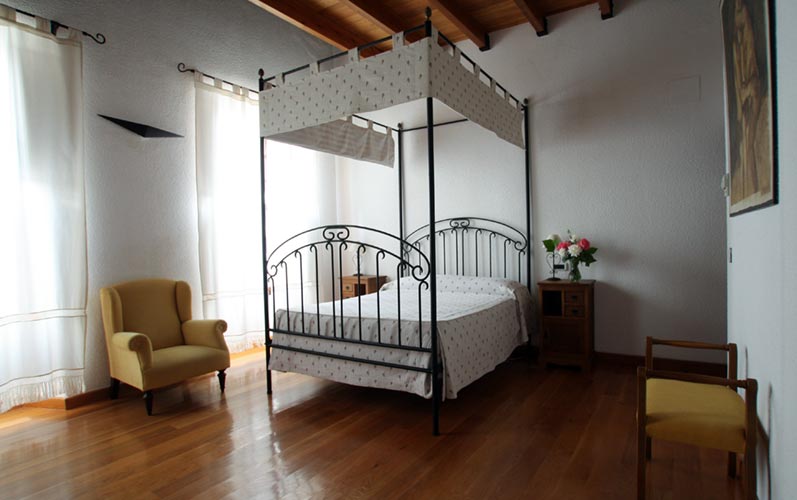 Un dormitorio con una cama con dosel y suelos de madera.