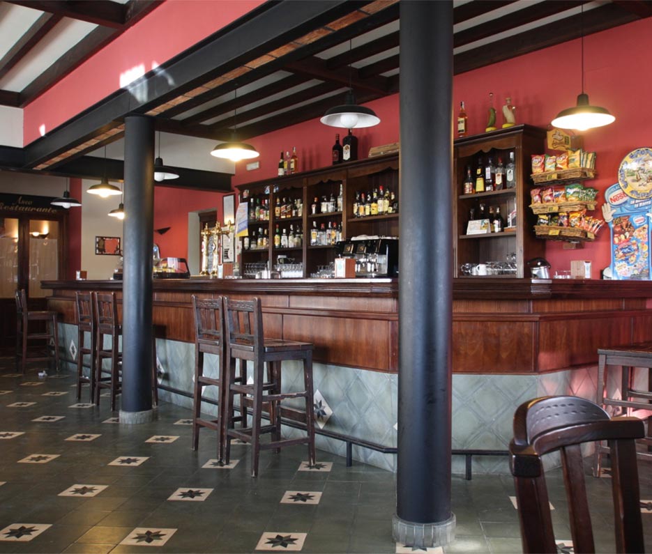 Una barra de un bar rústico con dos columnas negras.