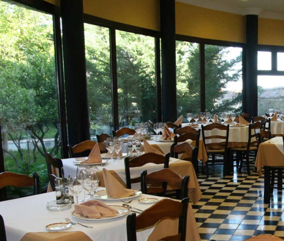 Restaurante con mesas y sillas con vistas a un jardín.