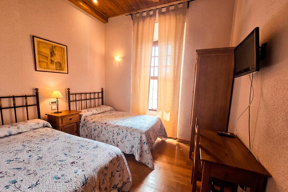 Habitación 102 Hotel Rural La Fábrica Fuente de Cantos Un dormitorio con una cama de madera, una mesita de noche y un sillón.