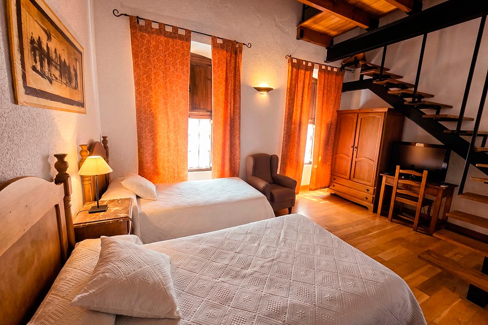 Habitación 202 Hotel Rural La Fábrica Fuente de Cantos Dormitorio de cama de matrimonio con dosel, suelo y techo de madera.