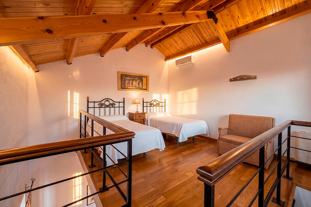 Habitación 205 Hotel Rural La Fábrica Fuente de Cantos Un dormitorio con una cama con dosel, escaleras y suelos de madera.