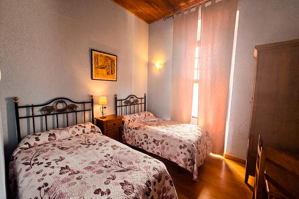 Habitación 106 Hotel Rural La Fábrica Fuente de Cantos Un acogedor dormitorio con una cama con dosel y una mesilla con un jarrón con rosas.