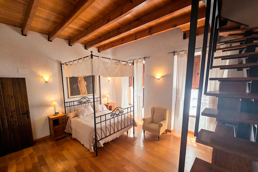 Habitación 201 Hotel Rural La Fábrica Fuente de Cantos Un acogedor dormitorio con una cama con dosel y una mesilla con un jarrón con rosas.