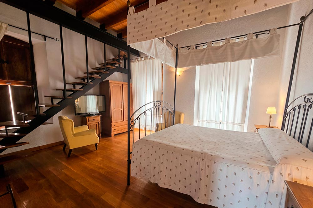 Habitación 207 Hotel Rural La Fábrica Fuente de Cantos Dormitorio con dos camas con techo abuhardillado de madera.