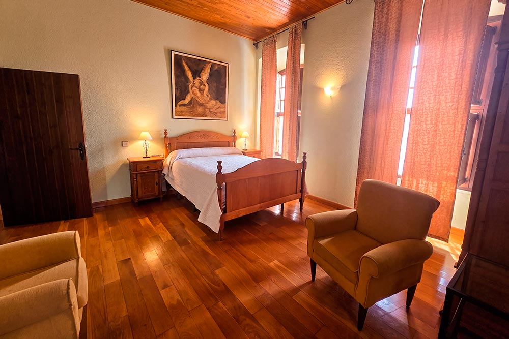 Habitación 101 Hotel Rural La Fábrica Fuente de Cantos Dormitorio con dos camas con techo abuhardillado de madera.