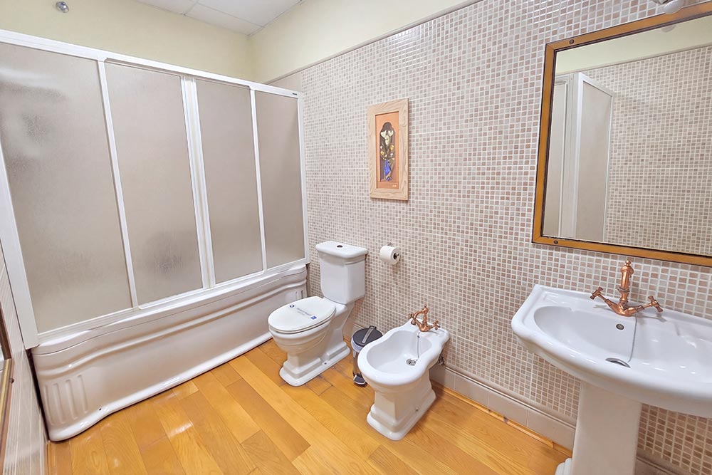 Habitación 205 Hotel Rural La Fábrica Fuente de Cantos Dormitorio con dos camas con cabecero de forja, suelo y techo de madera.