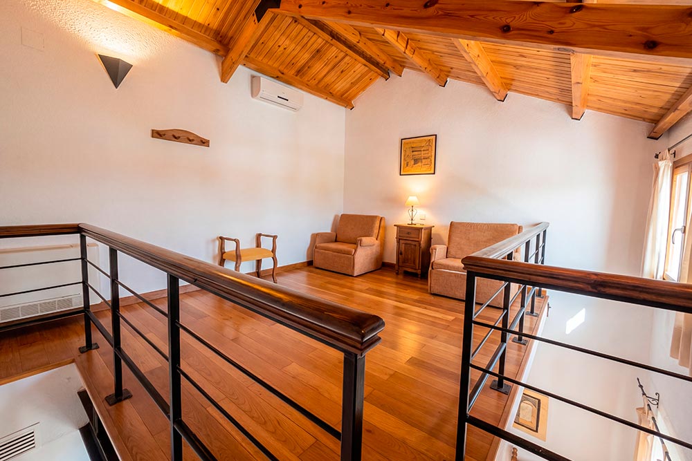 Habitación 107 HR La Fábrica Fuente de Cantos Un acogedor dormitorio con una cama con dosel y una mesilla con un jarrón con rosas.